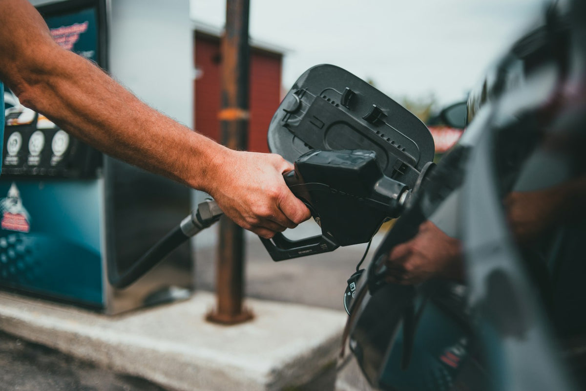 Driver holding a fuel nozzle at a petrol station